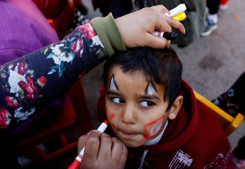 &copy; Reuters. امرأة تلون وجه طفل في مخيم للناجين من الزلزال في عثمانية بتركيا يوم الخميس. تصوير: صهيب سالم - رويترز. 