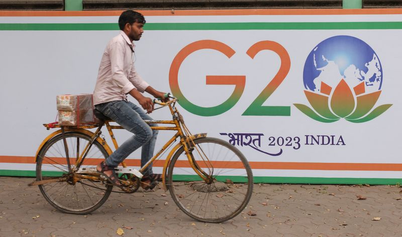 &copy; Reuters. FILE PHOTO: A man rides a bicycle past the hoarding of India's G20 presidency, on a street in Mumbai, India, December 15, 2022. REUTERS/Francis Mascarenhas