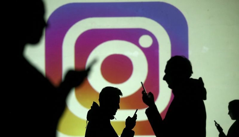 © Reuters. FILE PHOTO: Silhouettes of mobile users are seen next to a screen projection of the Instagram logo in this picture illustration taken March 28, 2018.  REUTERS/Dado Ruvic/Illustration/File Photo