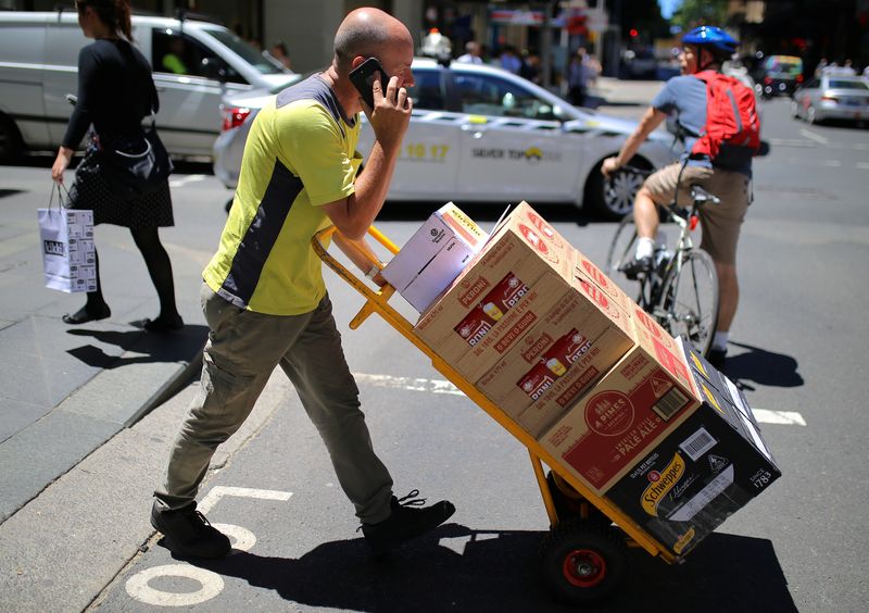 &copy; Reuters. FILE PHOTO: A worker talks on his phone as he pushes a trolley loaded with goods across a main road in a retail shopping area in central Sydney, Australia, November 15, 2017.  REUTERS/Steven Saphore