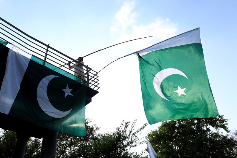 &copy; Reuters. FILE PHOTO: A boy uses a bamboo stick to adjust national flags at an overhead bridge ahead of Pakistan's Independence Day, in Islamabad, Pakistan August 10, 2018. REUTERS/Faisal Mahmood