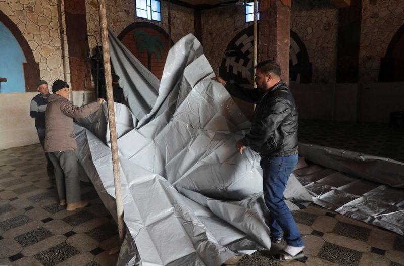 © Reuters. People set up a tent in a hall as they take shelter inside a venue, after they were struck by earthquakes in rebel-held Idlib, Syria February 21, 2023. REUTERS/Khalil Ashawi