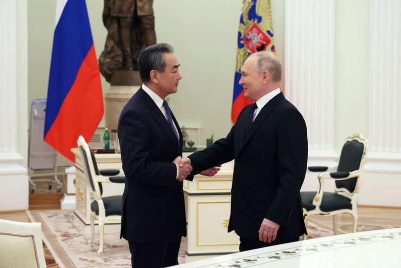 &copy; Reuters. Il presidente russo Vladimir Putin stringe la mano al direttore dell'Ufficio della Commissione centrale per gli affari esteri cinese Wang Yi durante un incontro a Mosca, Russia, 22 febbraio 2023. 