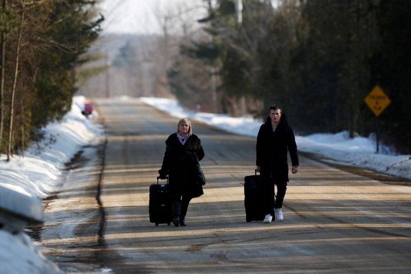 &copy; Reuters. FILE PHOTO: People walk with their luggage on Roxham Road before crossing the US-Canada border into Canada in Champlain, New York, U.S., February 14, 2018. Picture taken February 14, 2018.  REUTERS/Chris Wattie
