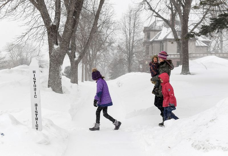 © Reuters. The Motz family walks through blowing snow as weather conditions worsen in Sioux Falls, South Dakota, U.S., February 22, 2023.  Erin Woodiel/Argus Leader/USA TODAY NETWORK via REUTERS