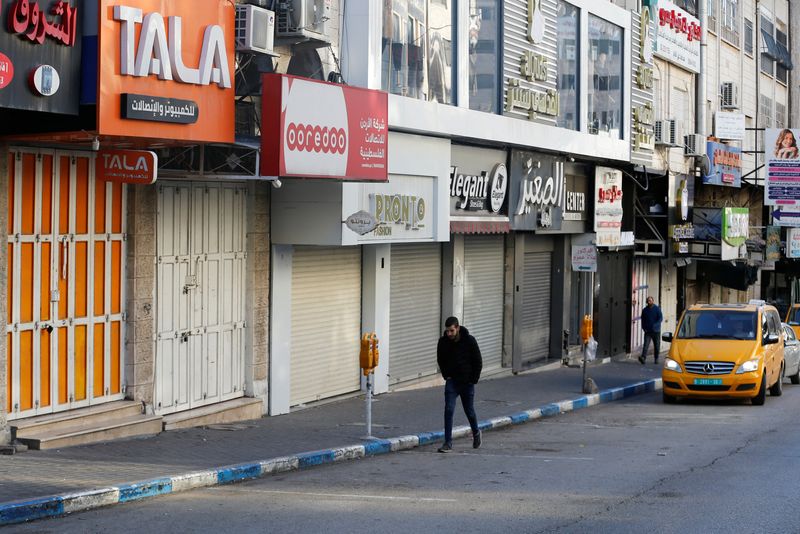 &copy; Reuters. فلسطينيون يسيرون بالقرب من محال مغلقة خلال غارة إسرائيلية في الخليل بالضفة الغربية المحتلة يوم الخميس. تصوير: موسى قواسمة – رويترز.