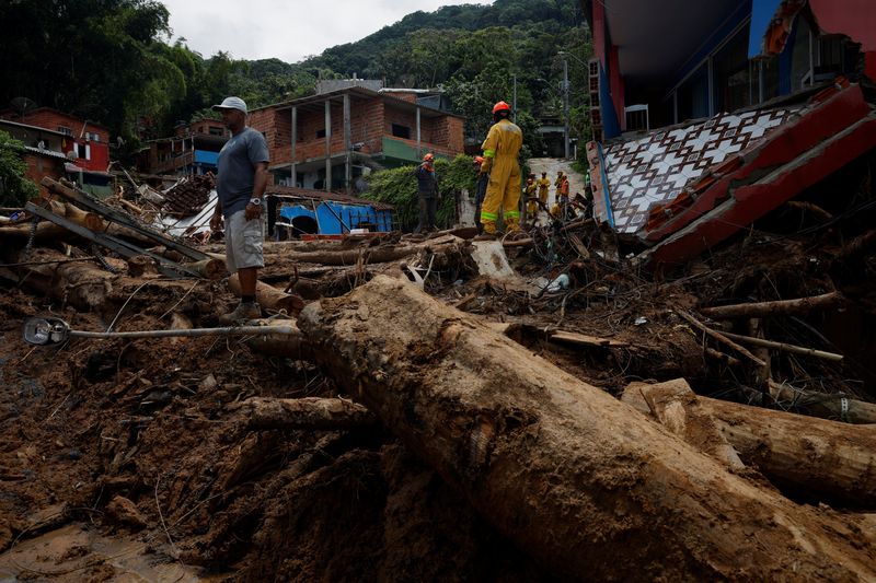 &copy; Reuters. Un hombre y los bomberos en uno de los sitios de deslizamiento de tierra después de las fuertes lluvias en Barra do Sahy, en Sao Sebastiao, Brasil, 22 de febrero 2023. REUTERS/Amanda Perobelli