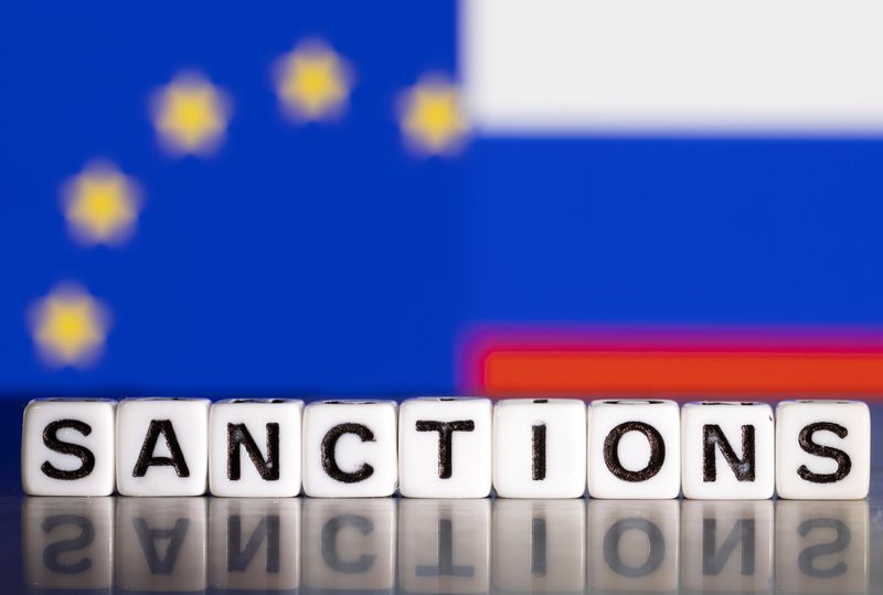 &copy; Reuters. Una bandiera Ue e una bandiera russa dietro a una serie di dadi con la scritta "Sanctions". REUTERS/Dado Ruvic