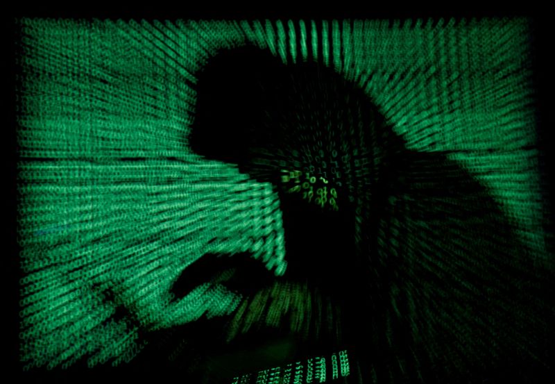 © Reuters. FILE PHOTO: A hooded man holds a laptop computer as cyber code is projected on him in this illustration picture taken on May 13, 2017.  REUTERS/Kacper Pempel/Illustration/