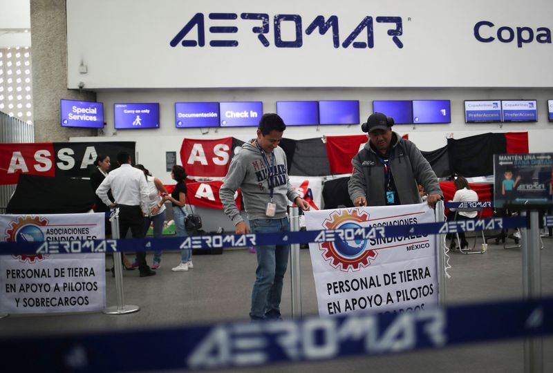 &copy; Reuters. FILE PHOTO: Workers of the airline Aeromar hold a banner that reads "Ground personnel in support of pilots" as they stand near the strike flags placed at the counters after the airline ended its operations, at the Benito Juarez International Airport, in M