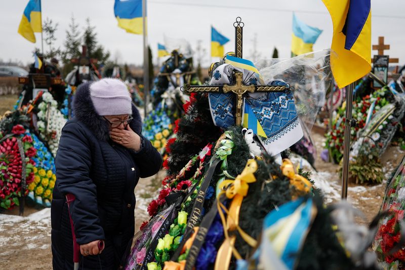 © Reuters. Mariia reacts near the grave of her son Vasyl Kurbet, Ukrainian service member killed in a fight against Russian troops, on a day of the first anniversary of Russia's attack on Ukraine, at a cemetery in the town of Bucha, outside Kyiv, Ukraine February 24, 2023.  REUTERS/Valentyn Ogirenko