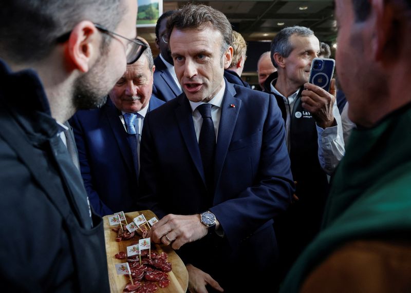 &copy; Reuters. Le président français Emmanuel Macron saisit un morceau de saucisson, le jour de l'inauguration de la 59e édition du salon de l'agriculture à Paris, en France. /Photo prise le 25 février 2023/REUTERS/Ludovic Marin