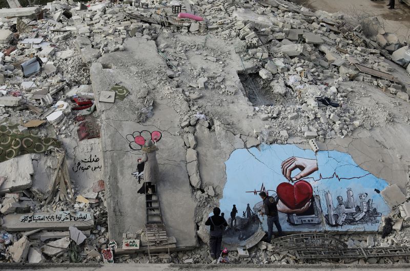 © Reuters. FILE PHOTO: Syrian artists Aziz Asmar and Salam Hamed paint street art on the rubble of damaged buildings in the aftermath of a deadly earthquake, in the rebel-held town of Jandaris, Syria February 22, 2023. REUTERS/Khalil Ashawi  