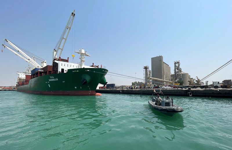 © Reuters. زورق خفر سواحل يبحر بجوار سفينة حاويات تجارية رست في ميناء الحديدة اليمني يوم السبت. تصوير: خالد عبد الله - رويترز