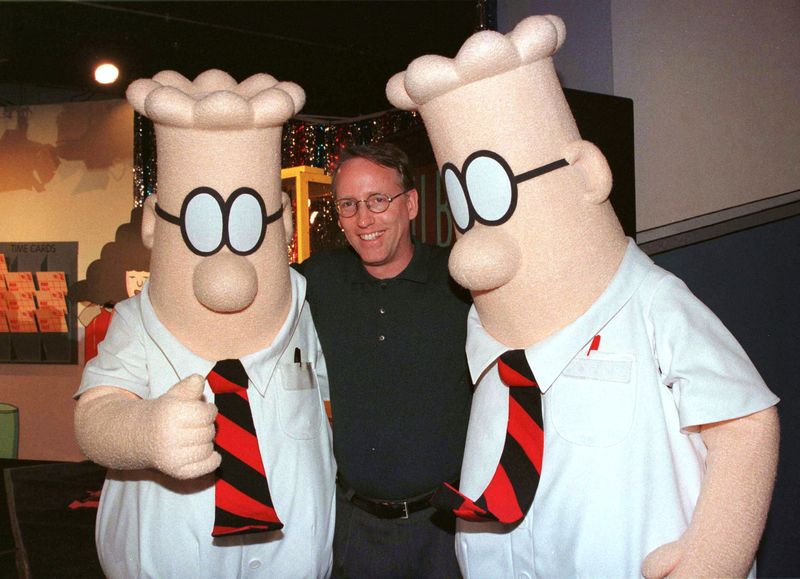 &copy; Reuters. FILE PHOTO: Scott Adams, the creator of "Dilbert", the cartoon character that lampoons the absurdities of corporate life, poses with two "Dilbert" characters at a party January 8, 1999 in Pasadena, Calif. REUTERS/Fred Prouser/File Photo