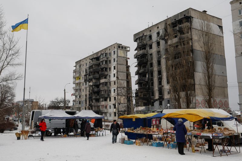 © Reuters. FILE PHOTO: Local residents buy food at a street market in front of apartment building heavily damaged in the beginning of Russia's attack on Ukraine, in the town of Borodianka, Kyiv region, Ukraine December 15, 2022. REUTERS/Valentyn Ogirenko