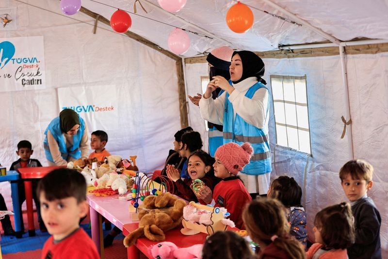 © Reuters. متطوعات يقمن بالغناء خلال أنشطة ترفيهية لدعم الصحة النفسية للاطفال المتضررين من الزلزال المميت في مخيم للناجين في أديامان بتركيا يوم 18 فبراير شباط 2023. تصوير: ثائر السوداني - رويترز.
