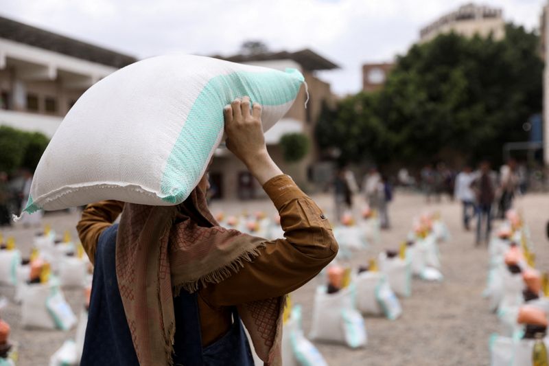 &copy; Reuters. عاملة تحمل كيسا من دقيق القمح أثناء توزيع مساعدات غذائية من قبل الجمعية الخيرية المحلية منى للإغاثة في صنعاء يوم 24 أبريل نيسان 2022. تصوير: خال