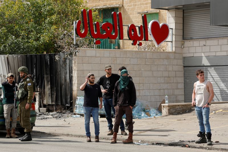 &copy; Reuters. Colonos israelíes junto a un miembro del ejército israelí, después de un incidente en el que un palestino armado mató a dos colonos israelíes, cerca de Hawara, en la Cisjordania ocupada por Israel, el 27 de febrero de 2023. REUTERS/Ammar Awad