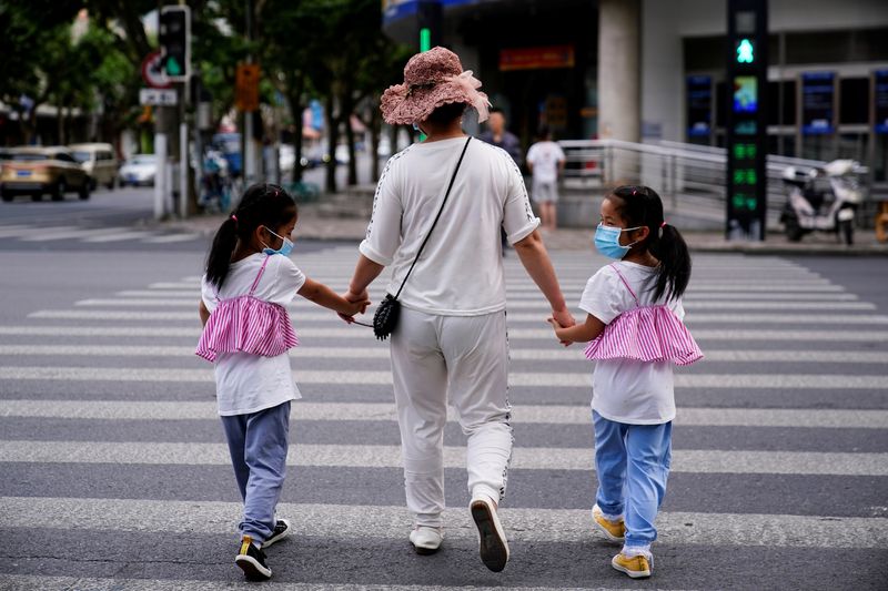 &copy; Reuters. FILE PHOTO: A mother walks with her twin daughters on a street in Shanghai, China June 7, 2021. REUTERS/Aly Song