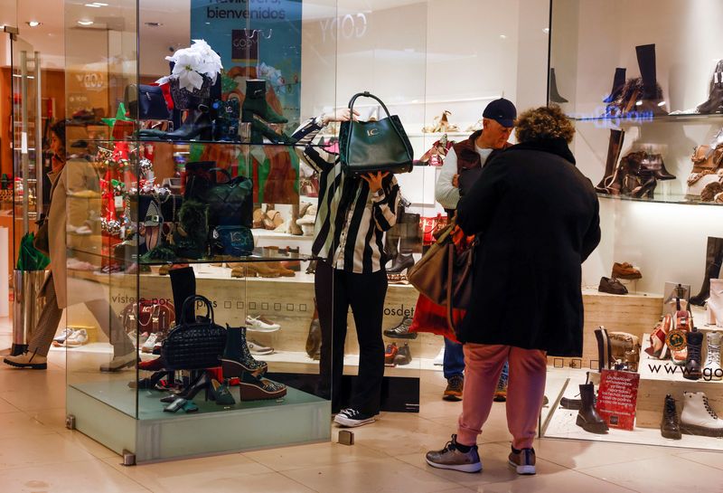 © Reuters. FILE PHOTO: A saleswoman shows a bag to customers in a shoe shop in Ronda, Spain, December 13, 2022. REUTERS/Jon Nazca