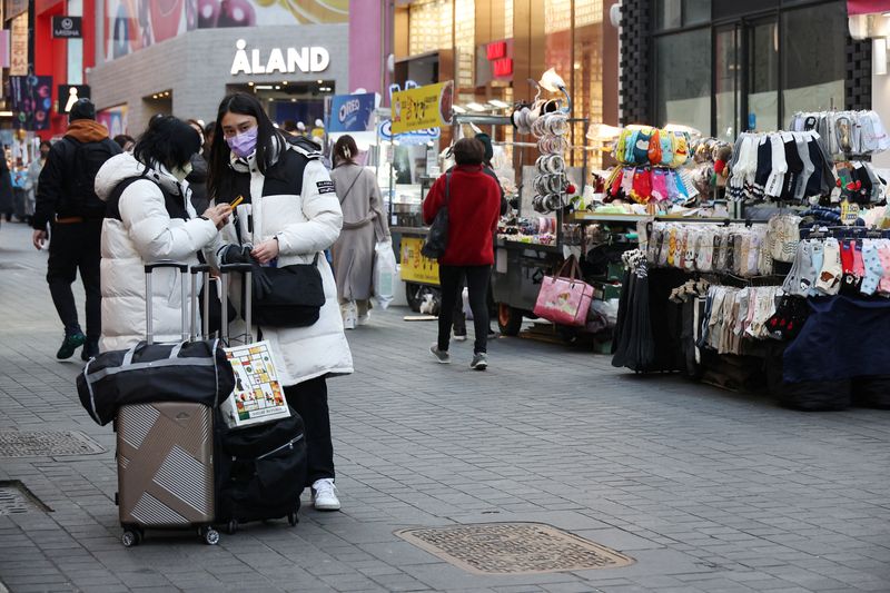 © Reuters. FILE PHOTO: Chinese tourists stand next to street vendors at Myeongdong shopping district in Seoul, South Korea, January 9, 2023. REUTERS/Kim Hong-Ji