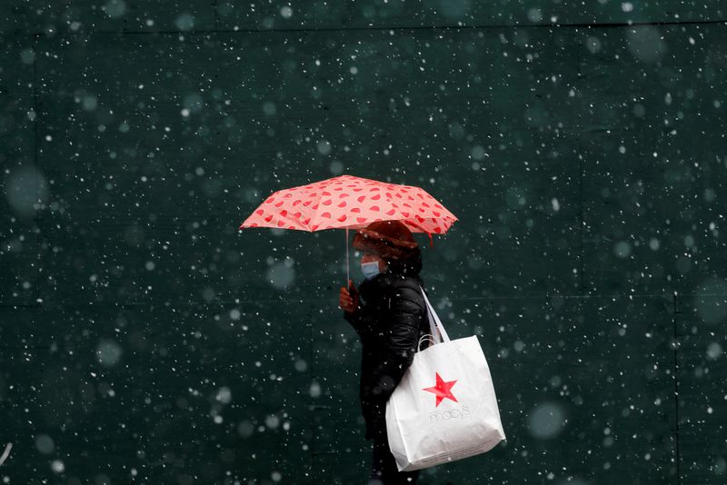 © Reuters. FILE PHOTO: A woman carrying a Macy's bag walks in falling snow as a winter storm moves into the northeast of the United States, in Times Square in New York City, New York, U.S., January 26, 2021. REUTERS/Mike Segar