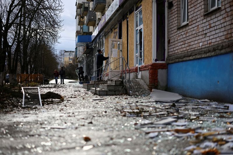 © Reuters. FOTO DE ARCHIVO: Una persona trabaja para cubrir las ventanas dañadas de un edificio tras un bombardeo, en medio del ataque de Rusia a Ucrania, en Kherson, Ucrania 21 de febrero de 2023. REUTERS/Lisi Niesner/Foto de archivo