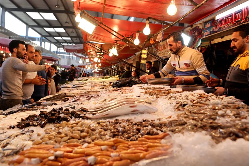 &copy; Reuters. FILE PHOTO: An Egyptian vendor shows different kinds of fish to customers at the new fish market at Port Said city, northeast of Cairo, Egypt January 5, 2023. REUTERS/Mohamed Abd El Ghany