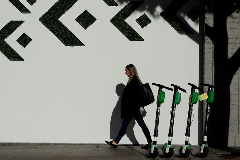 &copy; Reuters. FILE PHOTO: A woman walks past electric Lime scooters parked on the sidewalk in downtown Los Angeles, California, U.S., October 16, 2019.  REUTERS/Mike Blake/File Photo