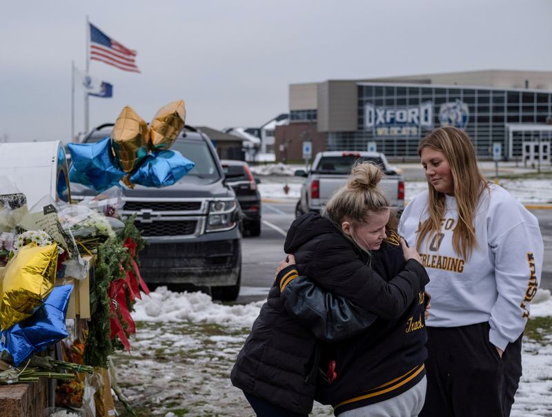 &copy; Reuters. FILE PHOTO: People embrace as they pay their respects at a memorial at Oxford High School, a day after a shooting that left four dead and eight injured, in Oxford, Michigan, December 1, 2021.  REUTERS/Seth Herald      