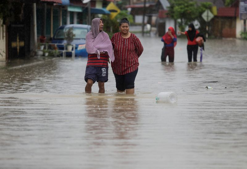 &copy; Reuters. السكان يخوضون مياه الفيضانات في بلدة يونج بينج بمنطقة باتو باهات في جوهور بماليزيا يوم السبت. تصوير: حسنور حسين - رويترز 
