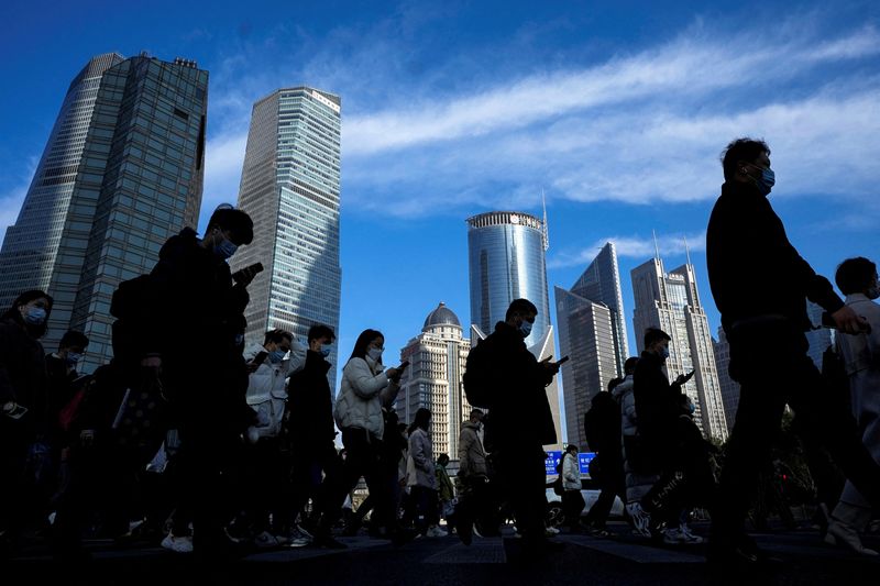 &copy; Reuters. FILE PHOTO: People cross a street near office towers in the Lujiazui financial district, ahead of the National People's Congress (NPC), in Shanghai, China, February 28, 2023. REUTERS/Aly Song 