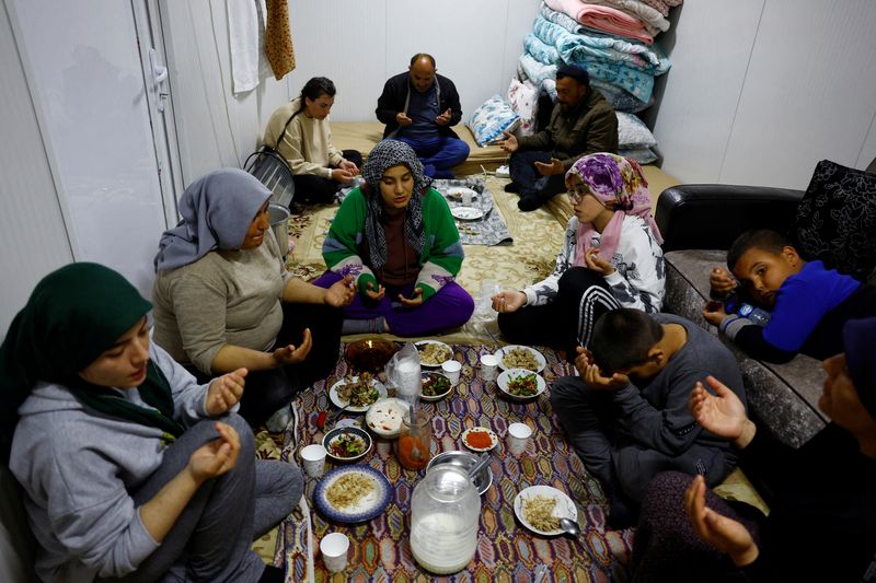 &copy; Reuters. Members of the Arslan family pray at dinner in one of the three container homes where they live by a petrol station after losing their homes in the aftermath of a deadly earthquake in Nurdagi, Turkey, March 4, 2023. REUTERS/Susana Vera