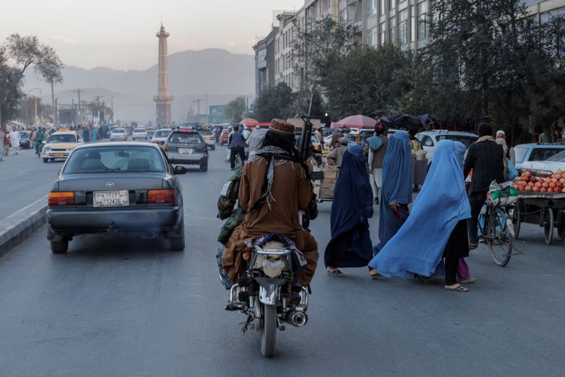 &copy; Reuters. FOTO DE ARCHIVO: Un grupo de mujeres con burka cruza la calle al paso de miembros de los talibanes en Kabul, Afganistán. 9 de octubre, 2021. REUTERS/Jorge Silva/Archivo