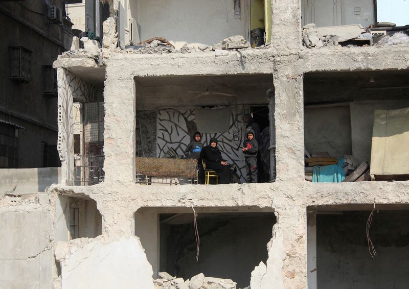 &copy; Reuters. سيدة سورية تجلس مع ابنها وأحفادها في منزلهم الذي لحق به الدمار جزئيا في حلب في أعقاب زلزال مدمر ضرب المنطقة. الصورة التقطت يوم 13 فبراير شباط 2