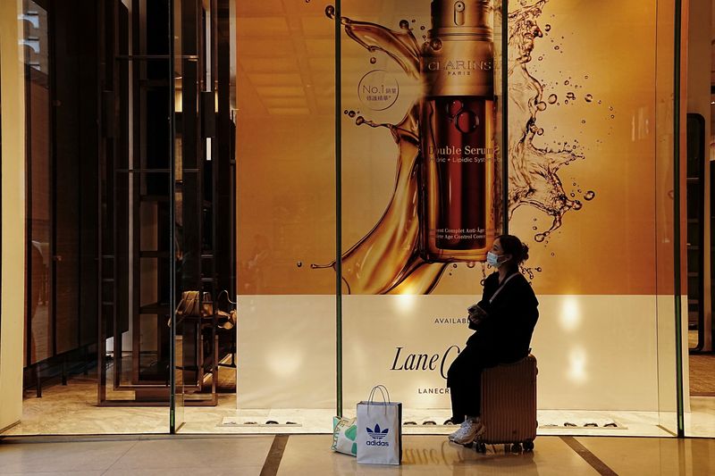 &copy; Reuters. A shopper sits in front of a Clarins advertisement displayed at a Lane Crawford luxury store at Tsim Sha Tsui district in Hong Kong, China February 15, 2023. REUTERS/Lam Yik
