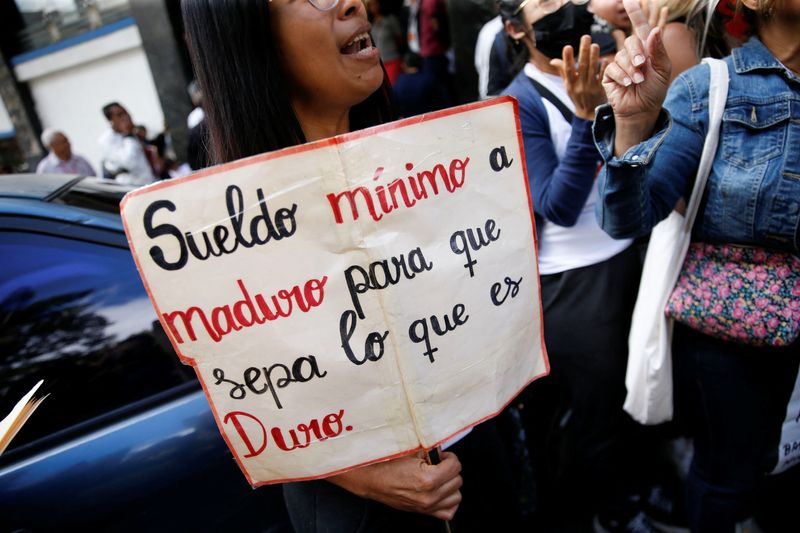 &copy; Reuters. FILE PHOTO: A teacher holds a sign reading "Minimum wage to Maduro to let him know how hard it is" during a protest demanding better salaries in Caracas, Venezuela February 23, 2023. REUTERS/Leonardo Fernandez Viloria