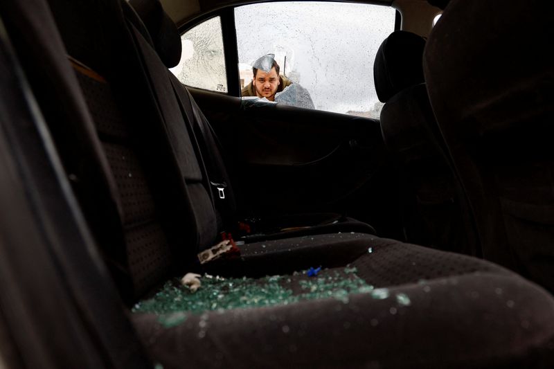© Reuters. فلسطيني يتفحص سيارته بعدما هاجمها مستوطنون إسرائيلون أثناء ما كان بداخلها مع أسرته في قرية حوارة بالضفة الغربية المحتلة يوم الثلاثاء. تصوير: رنين صوافطة - رويترز.
