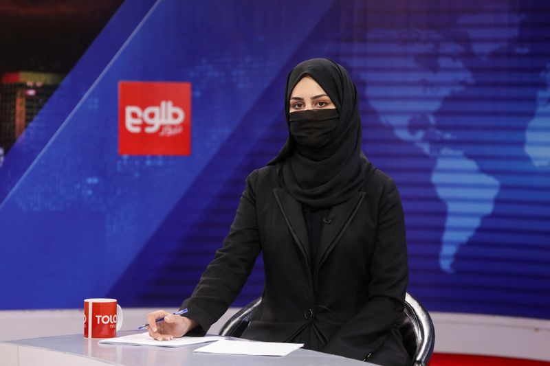 &copy; Reuters. FILE PHOTO: A female presenter for Tolo News, Khatereh Ahmadi, while covering her face, works in a newsroom at Tolo TV station in Kabul, Afghanistan, May 22, 2022. REUTERS/Ali Khara