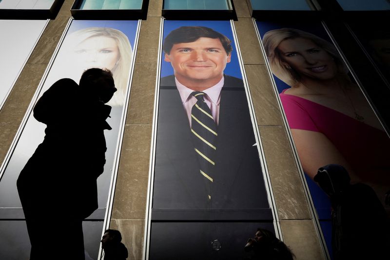 &copy; Reuters. FILE PHOTO: People pass by a promo of Fox News host Tucker Carlson on the News Corporation building in New York, U.S., March 13, 2019. REUTERS/Brendan McDermid