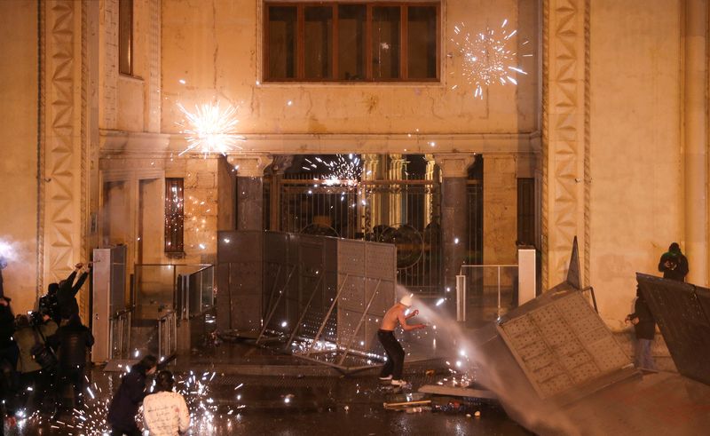 © Reuters. Fireworks explode outside the parliament building, as protesters attempt to break through barrier constructions during a rally against a draft law on 