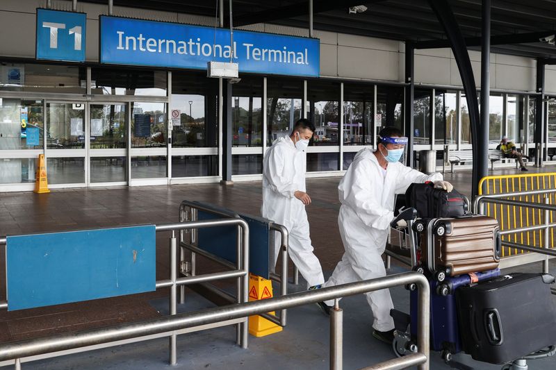&copy; Reuters. FILE PHOTO: Travellers in personal protective equipment depart the international terminal for a taxi stand at Sydney Airport, as countries react to the new coronavirus Omicron variant amid the coronavirus disease (COVID-19) pandemic, in Sydney, Australia,