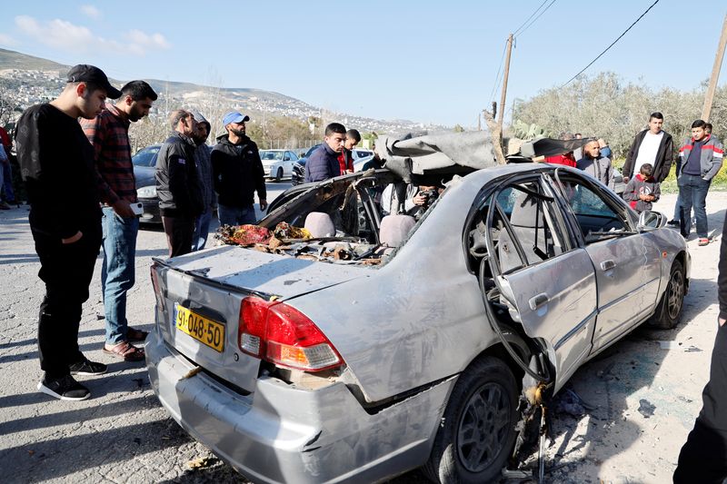 © Reuters. People look at a damaged car where three Palestinian militants were killed during an Israeli operation, near Jenin, in the Israeli-occupied West Bank, March 9, 2023. REUTERS/Raneen Sawafta