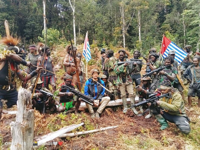 © Reuters. FILE PHOTO: A man who is identified as Philip Mehrtens, the New Zealand pilot who is said to be held hostage by a pro-independence group, sits among the separatist fighters in Indonesia's Papua region, March 6, 2023. The West Papua National Liberation Army (TPNPB)/Handout via REUTERS 