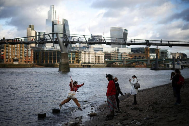 © Reuters. People stand on the bank of the River Thames with the City of London financial district in the background, in London, Britain, January 13, 2023. REUTERS/Henry Nicholls