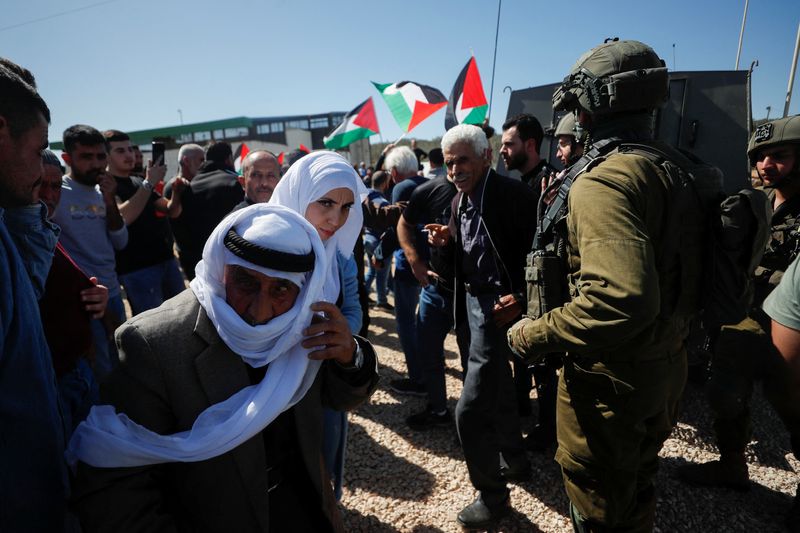 © Reuters. Palestinians take part in a protest against a new Israeli settlement as Israeli forces stand guard near their vehicle near Ramallah in the Israeli-occupied West Bank, March 10, 2023. REUTERS/Mohamad Torokman