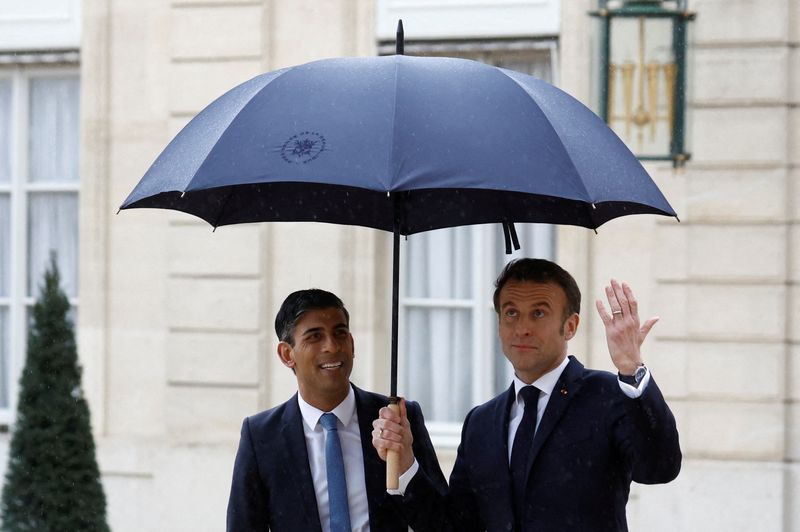 © Reuters. French President Emmanuel Macron and British Prime Minister Rishi Sunak react in the rain after the Franco-British Summit joint news conference held at Elysee Palace in Paris, France March 10, 2023. REUTERS/Gonzalo Fuentes