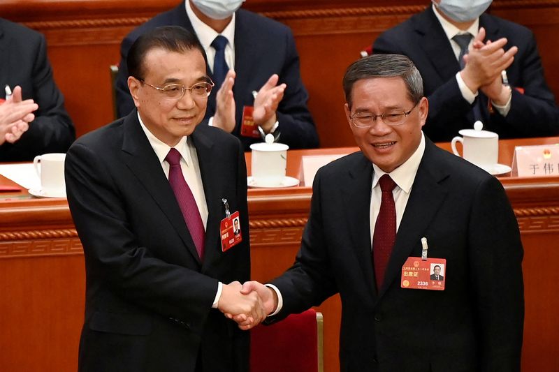 &copy; Reuters. 　中国の新首相に元上海市トップで習近平国家主席に近い李強氏（写真、右）が１１日、全国人民代表大会（全人代）での選出を経て就任した。写真は退任する李克強氏と握手する李強氏。