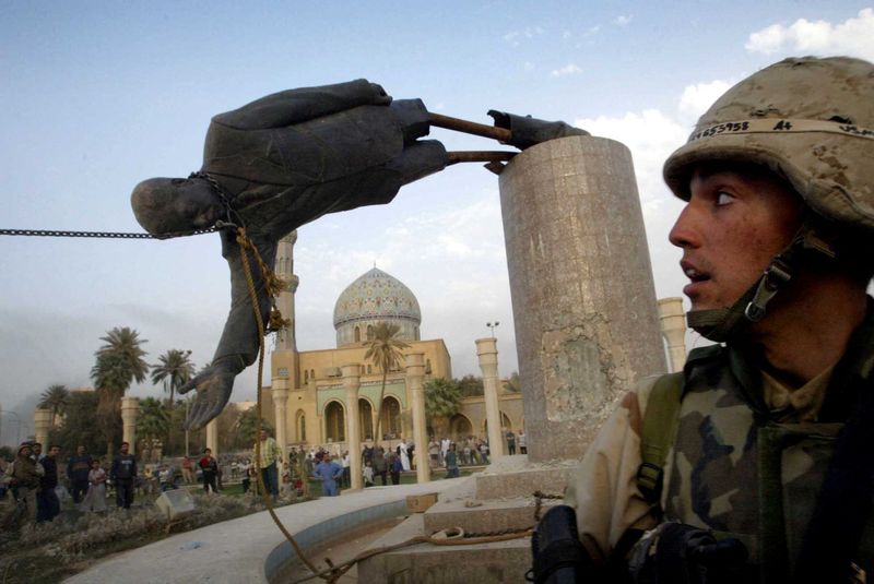 &copy; Reuters. جندي أمريكي يشاهد إسقاط تمثال صدام حسين ببغداد في التاسع من أبريل نيسان عام 2003. صورة من أرشيف رويترز.